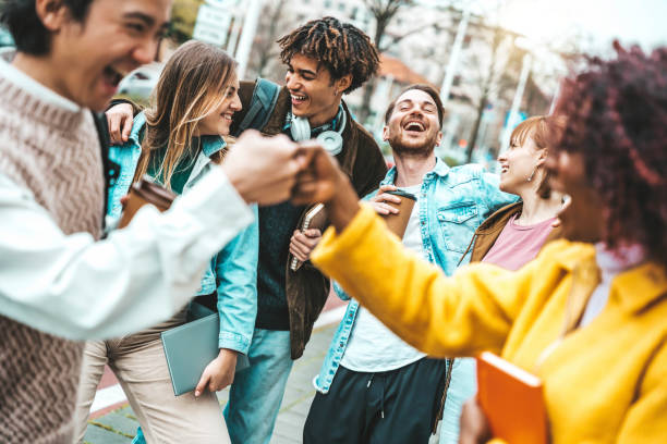 Happy multiracial friends having fun walking on city street - Group of different university students enjoying time together outside - Life style concept with guys and girls going out on summer day stock photo