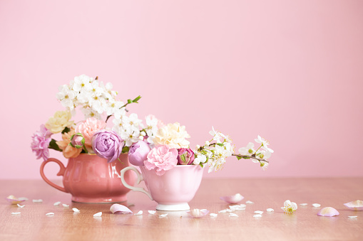 beautiful spring flowers in two vintage cups on pink background
