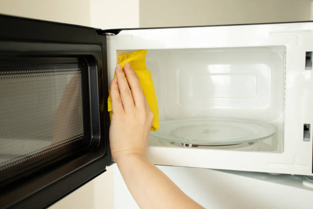 istock a woman's hand washes a microwave with a rag, cleanliness and hygiene in the kitchen 1476226679