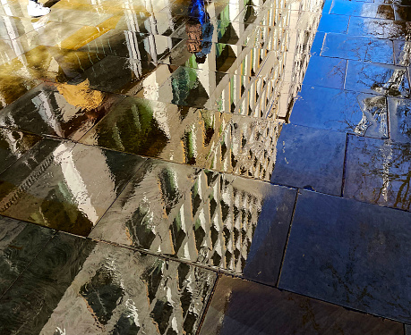 Reflections of buildings in a pavement on a rainy day