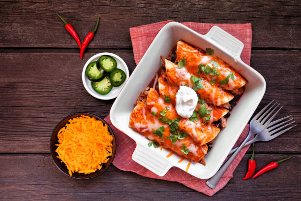 Chicken enchiladas, top view table scene on dark wood