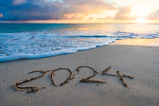 2024 year number handwritten on a sandy beach at sunrise