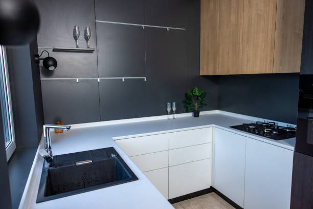 Interior of a comfortable kitchen with new furniture Cozy modern kitchenette with the white cabinets and black walls decorated in the minimalist style modern cottage interior design stock pictures, royalty-free photos & images