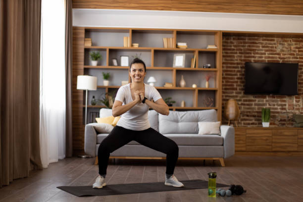istock Young woman doing squats during home workout 1476236889