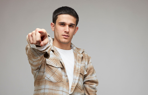 Young male pointing at the camera with his index finger.