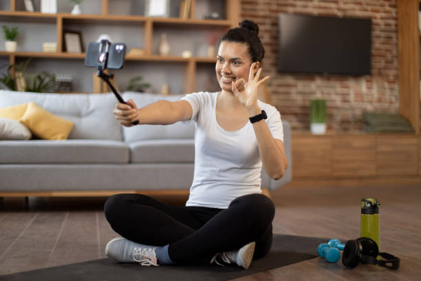 istock Young coach live streaming fitness tutorial via cell phone 1476239696