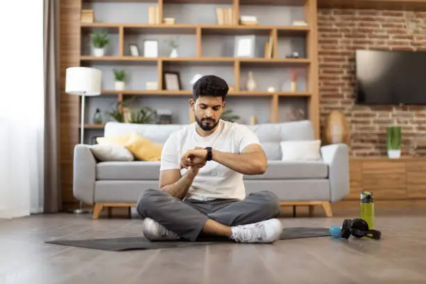 Photo of Young male using fitness tracker for home training