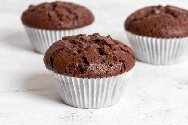 istock Plain chocolate muffins with chocolate chips in white paper cups. 1476241655