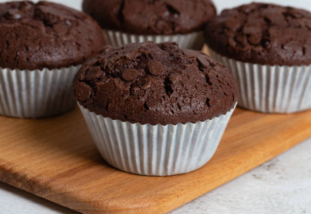 istock Plain chocolate muffins with chocolate chips in white paper cups. 1476241670