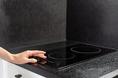 closeup of woman turn on induction hob at kitchen