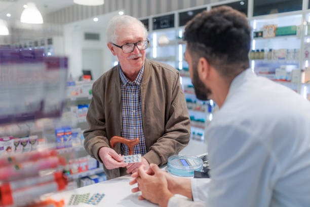 Young pharmacist explaining to customer how to dosing medication. stock photo