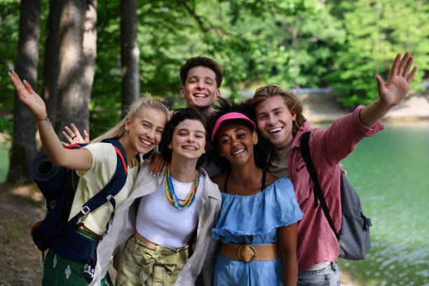 Group of young friends on camping trip near lake in summer. stock photo