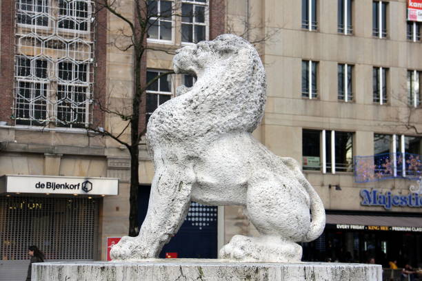 A stone lion sculpture with detailed carvings rests on a historic staircase in Gdańsk Old Town, Poland. The background showcases decorative architectural elements, including golden embellishments and intricate reliefs on the stone railing.