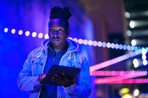 Young Man Using a Digital Tablet in a City at Night