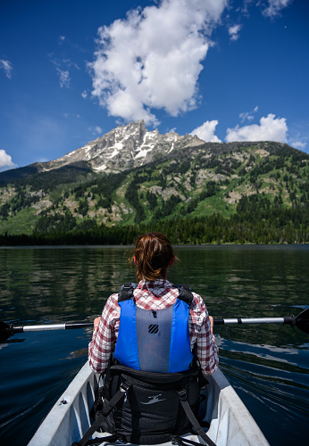 Woman Kayaks in Summer Below Teton Mountains
