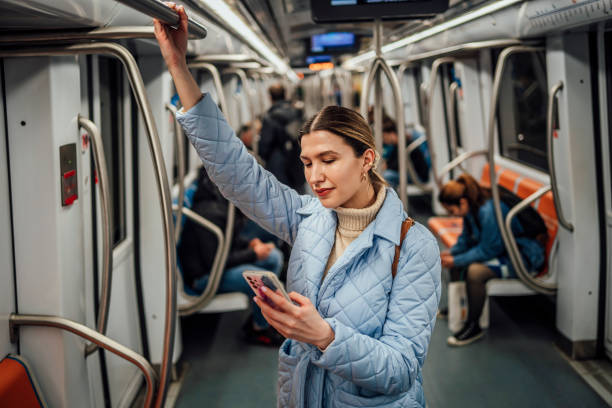 Woman using phone on a subway train stock photo