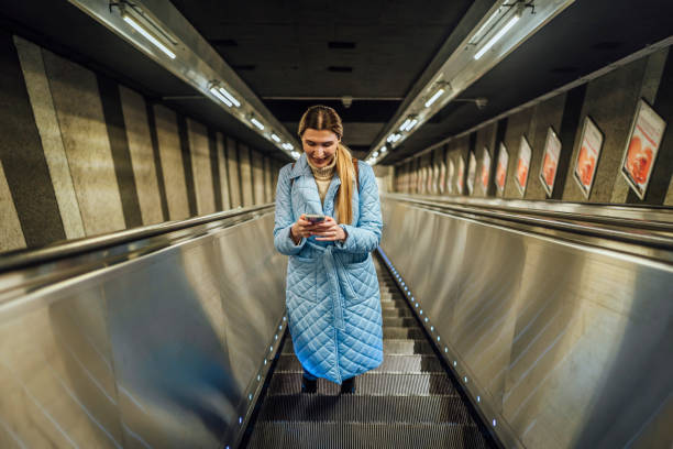 istock Young woman using phone in subway escalator 1476272874