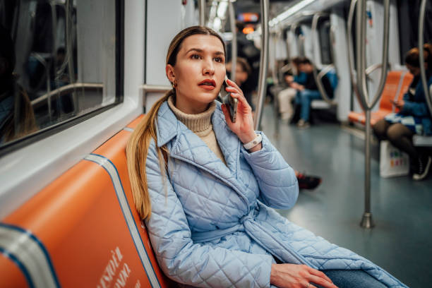 Young woman talking on the phone on a subway train