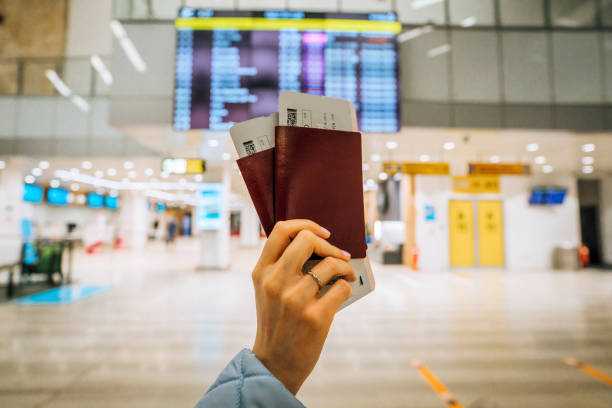Woman holding passports in front of a flight information board stock photo