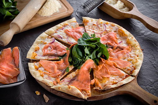 Delicious mixed pizza with salmon, mozzarella, pepper. Italian food image.