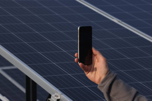 istock Man using smarth phone in front of solar panels 1476274665
