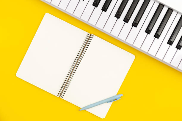 istock Piano and notebook on yellow background, flat lay, copy space. 1476277498