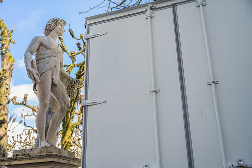 antique stone statue next to lorry