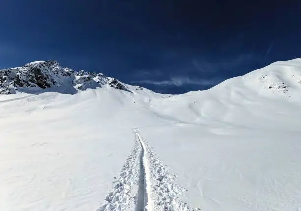 Ski tourers make a lonely track through the deep snow in the mountains above Davos. Ski mountaineering in the Swiss Alps. Skitouring, ski tour, skitour, skimo. High quality photo