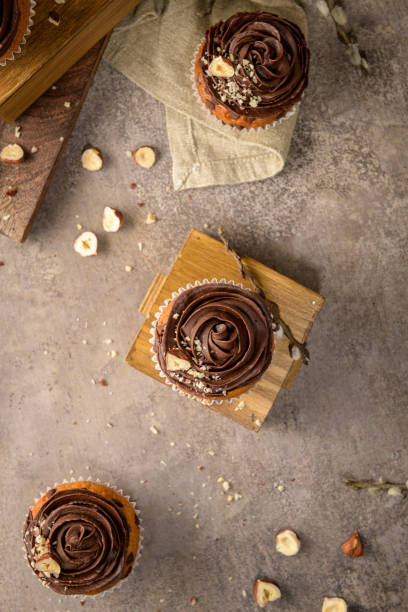 Chocolate chip muffins decorated with chocolate ganache and hazelnut on a vintage dark kitchen countertop.