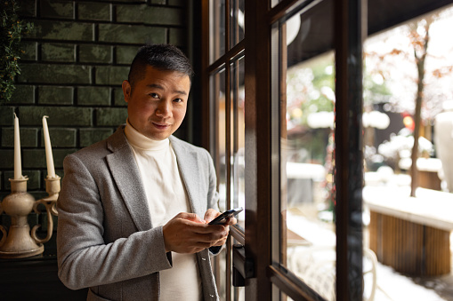 Global nature of modern business, showcasing a Chinese businessman in an upscale restaurant, connecting with the world via his mobile phone. The sense of cosmopolitanism and sophistication