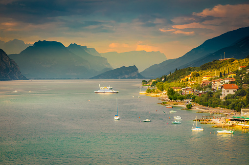 Lake Garda at dramatic Sunset, Malcesine village and boats, sailboats, Northern Italy