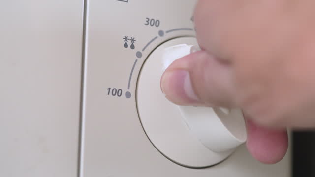 Close-up Hand turning on the temperature and timer oven switch of electric stove in home kitchen