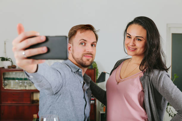 istock couple taking a selfie with smartphone at home - posting in social network 1476302599