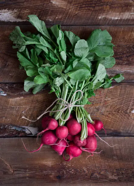 Photo of A bunch of fresh red radishes on top of rustic wooden table