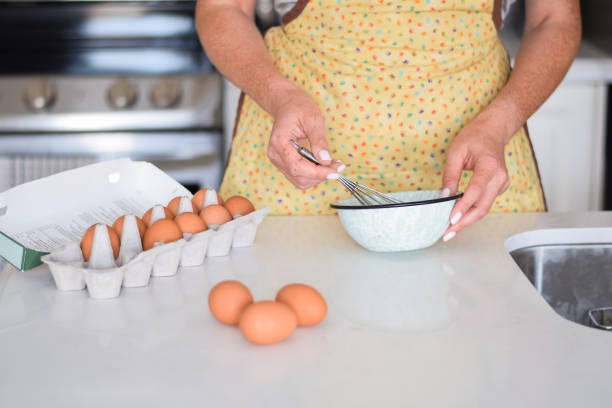 istock Woman is whisking eggs in a bowl on kitchen counter at home 1476306988