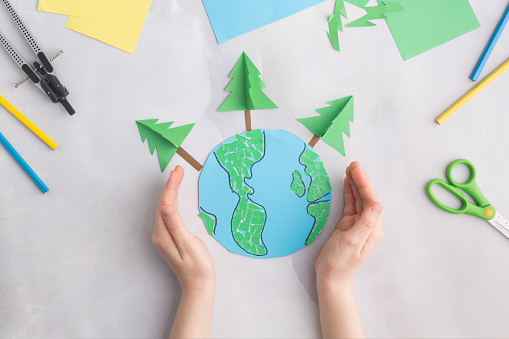 earth cut from paper around trees earth day concept kid's paper craft. High quality photo