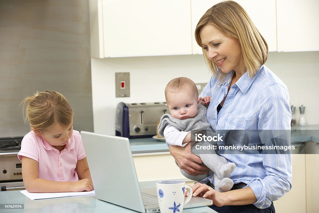 Mother with children using laptop in kitchen Mother with children using laptop at home in kitchen Baby - Human Age Stock Photo