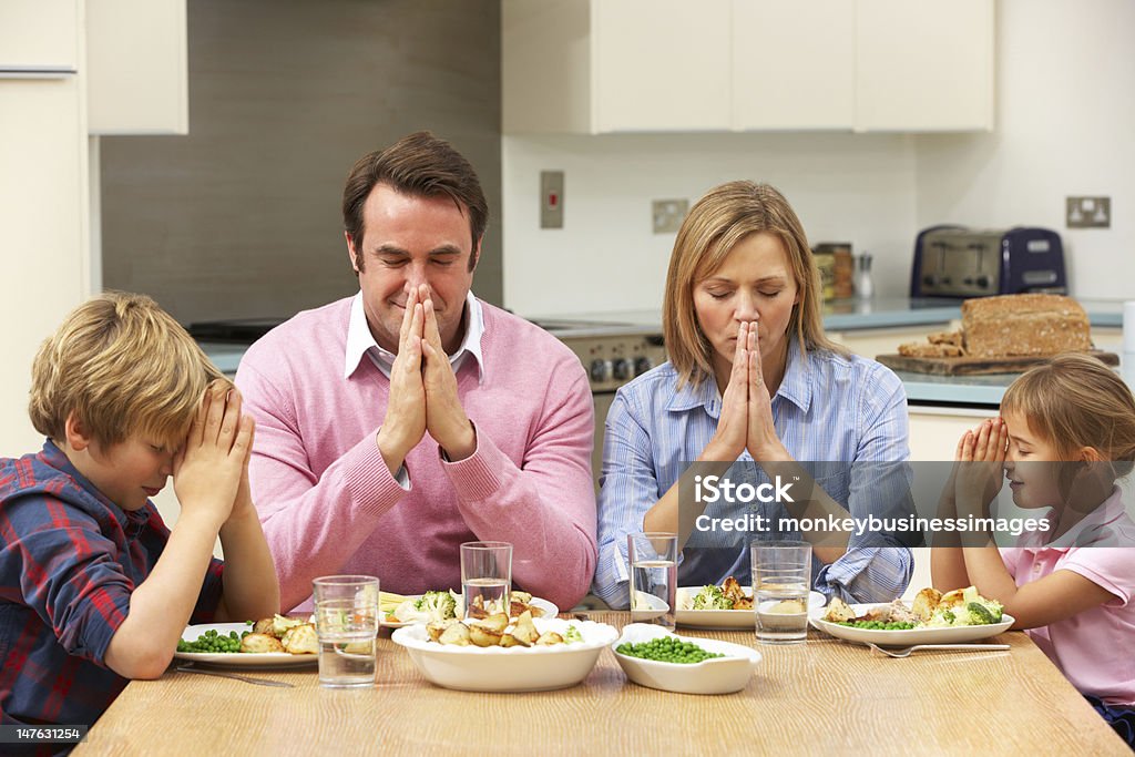 Family saying grace before meal Family saying grace before meal sitting around dining table at home 4-5 Years Stock Photo