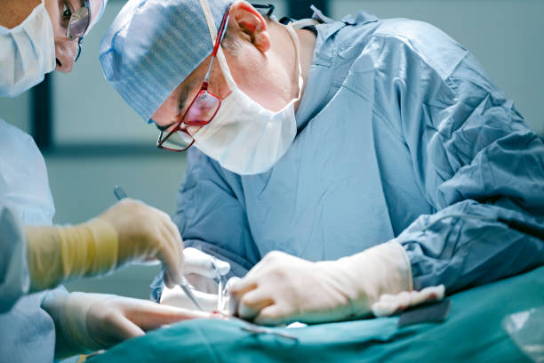 Surgeon performing surgery in full medical gear stock photo