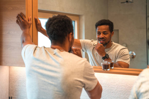 istock Attractive Multiracial Man Brushing His Teeth In Front Of The Mirror 1476341895