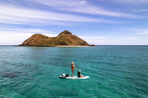 Mother and daughter paddleboarding at Lanikai Beach, Oahu. Active family on vacation.