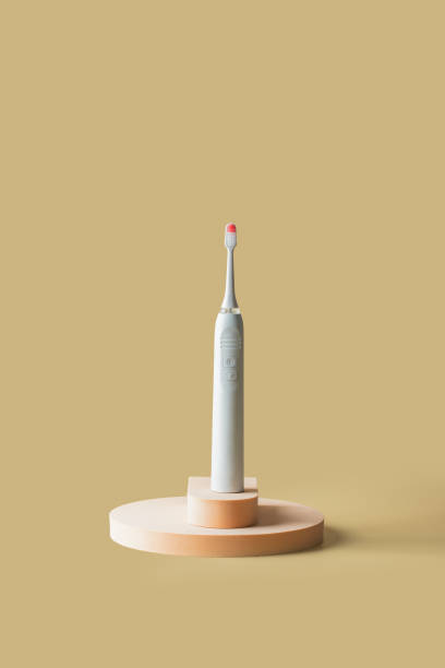 istock White pink electric toothbrush on the podiums on beige background. Copy space 1476342191