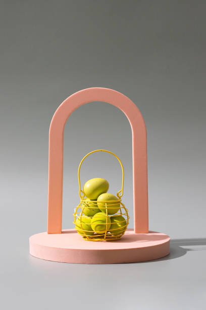 istock Easter eggs into the yellow basket on beige modern podium at green background with shadow. Copy space 1476342192