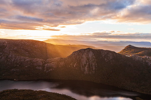 Rolling mountain terrain in cradle mountain national park in golden morning light with sun rays. Tasmania, Australia.