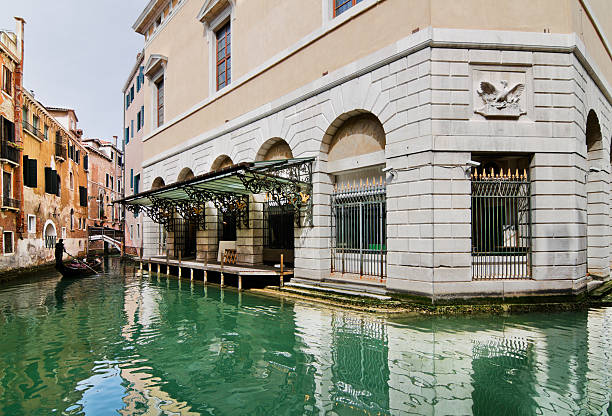 Gondolier transports tourists through one of Venice water channels near the famous Gran Teatro La Fenice