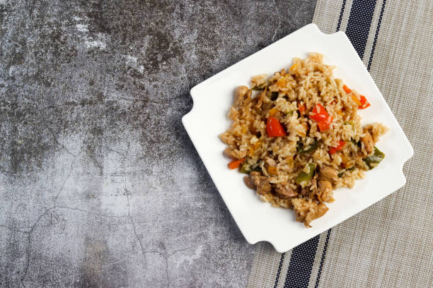 istock Chicken Bell Pepper Rice on a white square  plate on a dark background. Top view, flat lay 1476377915