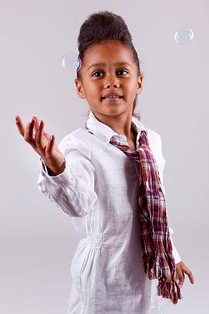istock Little African Asian girl blowing soap bubbles 147642443