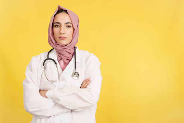 une femme médecin musulmane sérieuse avec les bras croisés regardant la caméra - clothing professional occupation medical occupation doctor photos et images de collection