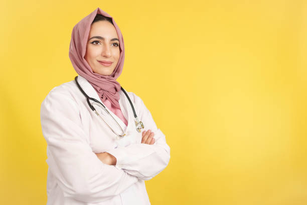 une femme médecin musulmane heureuse, les bras croisés, détourne le regard - clothing professional occupation medical occupation doctor photos et images de collection