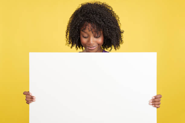 istock Woman with afro hair looking down to a blank board 1476425597